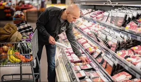  ?? Rene Jones Schneider / TNS ?? Neel Kashkari, president of the Federal Reserve Bank of Minneapoli­s, does the weekly family grocery shopping with his son Tecumseh in Wayzata, Minn. He said meat prices, especially for bacon, have more than doubled.