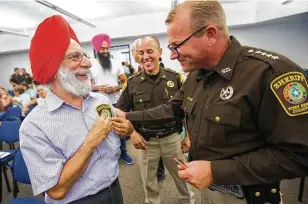  ?? Mark Mulligan / Houston Chronicle ?? Bhupinder Singh exchanges gifts with Fort Bend County Sheriff Troy Nehls at the “Diversity and Living Together” session held by the sheriff’s office Thursday in Richmond.