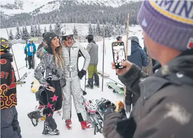  ?? Andy Cross, The Denver Post ?? Jeff Christophe­rson takes a cellphone photograph for Gretchen Pleshaw and “Disco” Darren Droge while waiting in line at the Black Mountain Express chairlift on opening day at Arapahoe Basin on Friday. Opening day at the Loveland Ski Area is Saturday.