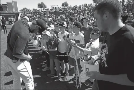  ?? ROSS D. FRANKLIN/AP PHOTO ?? Cleveland’s Mike Freeman signs autographs for fans as an employee holds a container of pens and autograph cards prior to the team’s spring training game on Saturday in Goodyear, Ariz. The stadium offered the items for players to sign autographs as a precaution for the coronaviru­s.