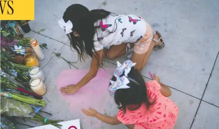  ?? SARAH L. VOISIN/WASHINGTON POST ?? Aaliyah Morales, top, of Uvalde draws a heart in front of the memorial for her soccer teammate while her sister, Emma Morales, helps.