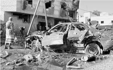  ??  ?? A man stands by a damaged car at the site of a car bomb attack outside the Finance Ministry offices in the southern port city of Aden. — Reuters photo