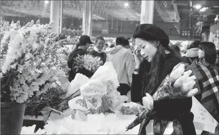  ?? SHI WENZHI / CHINA DAILY ?? A customer selects flowers at Dounan Flower Market in Kunming, Yunnan province, on Wednesday.