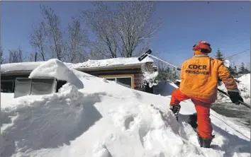  ?? A CAL FIRE Brian van der Brug Los Angeles Times ?? inmate crew member pushes snow off the roof of a residence at a Big Bear Lake trailer park.