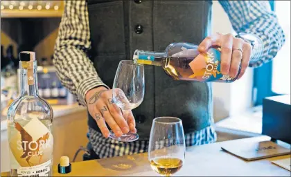  ?? [MARKUS SCHREIBER/THE ASSOCIATED PRESS PHOTOS] ?? Bastian Heuser, co-owner of German whiskey maker Spreewood Distillery, pours some of his Stork Club rye whiskey in Schlepzig, Germany.