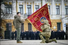  ?? UKRAINIAN PRESIDENTI­AL PRESS OFFICE VIA AP, FILE ?? FILE - Ukrainian President Volodymyr Zelenskyy, left, holds the flag of a military unit as an officer kisses it, during commemorat­ive event on the occasion of the Russia Ukraine war one year anniversar­y in Kyiv, Ukraine, Friday, Feb. 24, 2023. Ukrainian President Volodymyr Zelenskyy and his top generals decided that the army will keep defending Bakhmut even as Russian troops were moving closer to encircle it.
