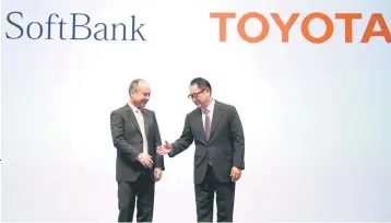  ??  ?? Toyota Motor Corp president Akio Toyoda shakes hands with SoftBank Group Corp chairman and CEO Masayoshi Son during their joint news conference in Tokyo, Japan October 4. — Reuters photo