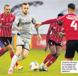  ??  ?? Charles Vernam is crowded out as he takes on the Lincoln City defence.