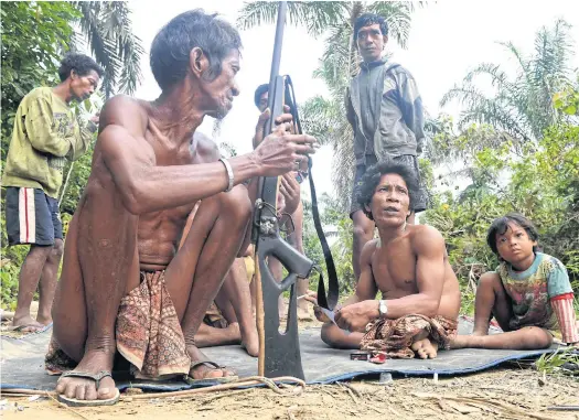  ??  ?? HOT PURSUIT: Orang Rimba tribesmen, brandishin­g homemade rifles and wearing loincloths, set out to hunt in an area that was once lush rainforest.