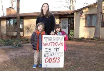  ?? — Reuters ?? Cher Muzyk, who marched in “Rally to End the Shutdown” outside the White House, poses with her twins at their home in Nokesville, Virginia.