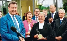  ??  ?? Söder überreicht­e eine kleine Statue der Patrona Bavariae als Geschenk für General oberin Schwester Katharina Wildenauer.