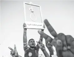  ?? — AFP photo ?? A Sudanese protester holds a hanging rope as others flash victory sign during a protest outside the army headquarte­rs in the capital Khartoum.