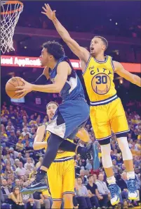  ?? MARCIO JOSE SANCHEZ/THE ASSOCIATED PRESS ?? Minnesota Timberwolv­es’ Tyus Jones, left, drives to the basket as the Golden State Warriors’ Stephen Curry (30) defends during their game Tuesday in Oakland, Calif.