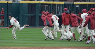  ?? NWA Democrat-Gazette/J.T. WAMPLER ?? Members of the Arkansas Razorbacks try to run down Dominic Fletcher after his game-winning hit beat Southern California 7-6 in eight innings Sunday at Baum Stadium in Fayettevil­le.