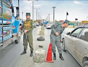  ?? AFP ?? Afghan policemen stand guard at a checkpoint along the road in Kabul on Saturday