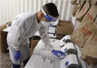  ?? Ross D. Franklin, The Associated Press ?? Berto Cortez, a CVS pharmacy technician, shows how COVID-19 tests are processed in a testing area set up by CVS at St. Vincent de Paul medical clinic Monday in Phoenix.