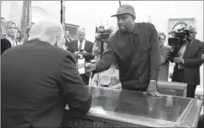  ?? EVAN VUCCI / ASSOCIATED PRESS ?? Kanye West shows President Donald Trump a photograph of a hydrogen plane Thursday during a meeting in the Oval Office.