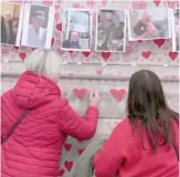  ?? ALASTAIR GRANT/AP ?? Family members write a message Tuesday to two sisters who died of COVID on the National COVID Memorial Wall in London.