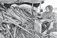  ?? -Gambar Bernama ?? PEKERJA arang kayu Siti Romlah Osman, 62, (kanan) bersama beberapa pekerja lain melakukan kerja-kerja membungkus arang kayu selepas dikeluarka­n dari ‘gok’ iaitu ketuhar (tempat pembakaran arang tertutup) ketika ditemui di Kampung Kolam, Jalan Merang baru-baru ini.