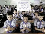  ??  ?? Tienen fe. En escuelas de Tailandia oran para pedir que todo el equipo Jabalíes salga con vida de las grutas.