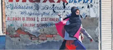  ?? Associated Press ?? ↑
A protesting Kashmiri girl throws stones at policemen in Srinagar.