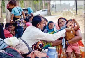  ??  ?? A migrant feeds his child before boarding a bus for Ludhiana to travel to their native places, during the ongoing COVID-19 lockdown, in Amritsar, on Thursday