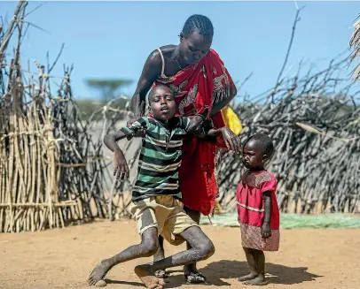  ?? AP ?? A mother helps her malnourish­ed son stand after he collapsed near their hut in the village of Lomoputh in northern Kenya. Russian, French and American leaders are crisscross­ing Africa to win support for their positions on the war in Ukraine, an intense competitio­n for influence the continent has not seen since the Cold War.