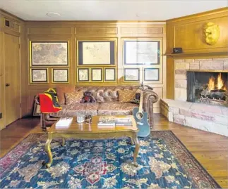  ??  ?? THE DEN retains the home’s original traditiona­l style. Its f loor-to-ceiling wood paneling, goldframed maps, brown sofa and oak coffee table make it feel like an old-world gentleman’s library.