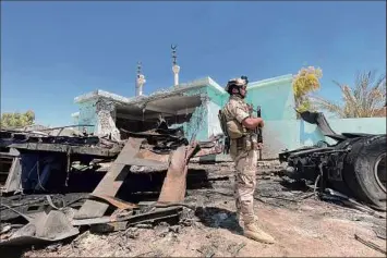  ?? Ayman Henna / Getty Images ?? Iraqi security soldier stands by destroyed vehicle that was carrying rockets amid sacks of flour, in al-baghdadi in al-anbar province. A nearby base hosting U.S. troops was hit by 14 rockets July 7. Iraq’s prime minister wants Pres. Joe Biden to name a U.S. withdrawal date.