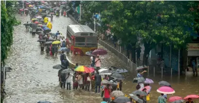  ?? PTI ?? People wade through a waterlogge­d street following heavy rain in Mumbai on Tuesday. —