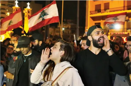  ?? AP ?? Protesters chant slogans and hold their national flags as they block a highway during an anti-government protest in Beirut on Wednesday.