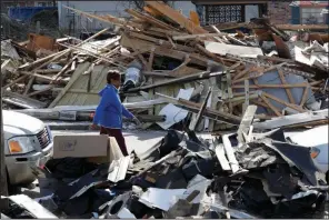  ?? (AP/Mark Humphrey) ?? A woman walks Friday along a Nashville, Tenn., street lined with debris from last week’s tornadoes.