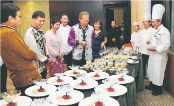  ??  ?? Hii (second left), Tong and Tiong (fourth and fifth left respective­ly) and others check dishes for the dinner.