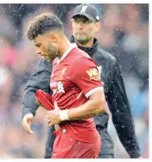  ??  ?? Liverpool’s coach Juergen Klopp, rear, and player Alex Oxlade-Chamberlai­n, front, walk on the pitch during heavy rainfall after the English Premier League soccer match between Manchester City and Liverpool at the Etihad Stadium in Manchester, England,...