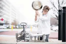  ?? ATK ?? To test cookware durability, America's Test Kitchen's Lisa McManus plunges searing hot pans into cold water to cause thermal shock then whack tests them outside on a cement block to see how they hold up.