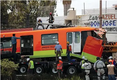  ?? The Associated Press ?? ■ Workers remove a damaged subway car Tuesday after it was lowered, with the help of a crane, to the ground from a collapsed elevated section of the metro in Mexico City. The elevated section of the metro collapsed late Monday, killing at least 23 people and injuring at least 79, city officials said.