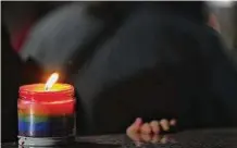  ?? Elizabeth Conley/Staff photograph­er ?? A lit rainbow candle flickers during a Houston vigil for the shooting victims at Club Q in Colorado.