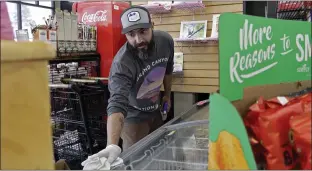  ??  ?? Mike Johnston, a clerk at the Maupin Market in tiny Maupin, Oregon, wipes down the ice cream case to protect customers from the new coronaviru­s.