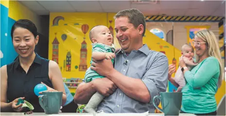  ?? CP PHOTO ?? Federal Conservati­ve leader Andrew Sheer holds four-month old Antonio Wang while caregiver Anna Yang watches at a Toronto child care facility where he gave an announceme­nt Tuesday.