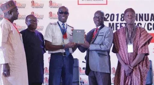  ??  ?? Flight Officer Aransi Adesola of Air Peace (c) receiving a service an NIPR merit award