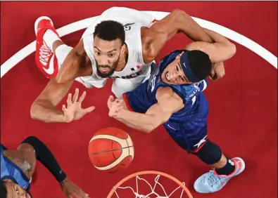  ?? (AP/Aris Messinis) ?? France’s Rudy Gobert (left) fights for a rebound with Devin Booker of the United States during a men’s basketball preliminar­y round game Sunday at the Tokyo Olympics in Saitama, Japan. France won 83-76 to snap the United States’ 25-game Olympic winning streak. More photos at arkansason­line.com/726olympic­s.