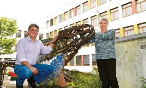  ?? Foto: Silvio Wyszengrad ?? Die Agnes-Bernauer-Realschule feiert: Schulleite­r Robert Fischer und seine Vorgängeri­n Gerlinde Kolb an der Drachensku­lptur in der „Grünen Oase“.