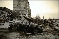  ?? ?? People sit by a collapsed building in Malatya, Turkey, on Tuesday.