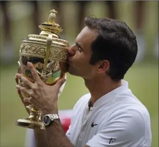  ?? TIM IRELAND, THE ASSOCIATED PRESS ?? Roger Federer celebrates with the trophy after beating Marin Cilic in the men’s singles final at Wimbledon.