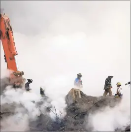  ?? Stan Honda / AP ?? In this Oct. 11, 2001, file photo, firefighte­rs make their way over the ruins of the World Trade Center through clouds of dust and smoke at ground zero in New York.