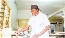  ?? (AFP) ?? Bonaventur­a Boma prepares bread in his bakery in Lome. Dressed in an apron, Boma
reprimands his employees out of the oven with still smoking rods.