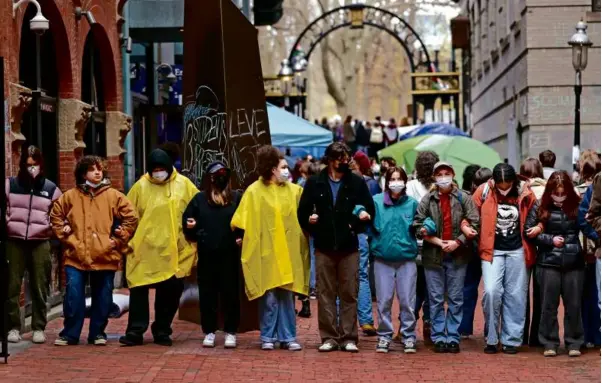  ?? DAVID L. RYAN/GLOBE STAFF ?? Pro-Palestinia­n student protesters at Emerson College locked arms in front of an encampment at Boylston Place on Wednesday.