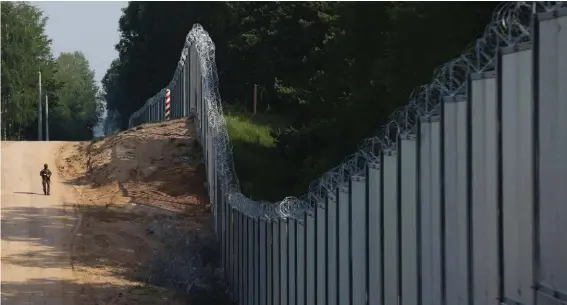  ?? ?? A Polish border guard patrols the area of a newly built metal wall on the border between Poland and Belarus, near Kuznice, Poland, Thursday, June 30, 2022. When relations with Belarus deteriorat­ed after its authoritar­ian President Alexander Lukashenko was declared the winner of an election widely seen as fraudulent, the government in Minsk sent thousands of migrants streaming across the EU's frontiers. In response, Poland and Lithuania erected walls along their borders with Belarus. (AP Photo/Michal Dyjuk, File)