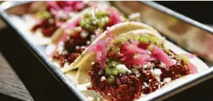  ?? Steve Gonzales / Houston Chronicle ?? Finished cochinita pibil tacos, topped with pickled onions and habanero salsa, are served at Goodnight Charlie’s. Recipe, page D8