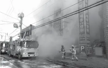  ?? AGENCE FRANCE PRESSE ?? Firefighte­rs try to put out a fire at a hospital building engulfed by heavy grey smoke in Miryang.